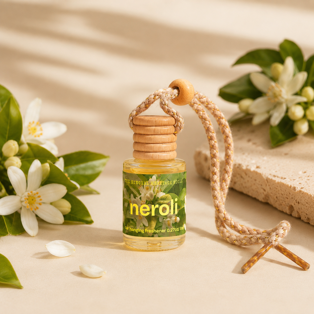Neroli car hanging freshener with braided cord among white flowers and green leaves